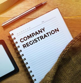 Notebook on a wooden desk titled 'Company Registration' with a pen resting above it, viewed from above.