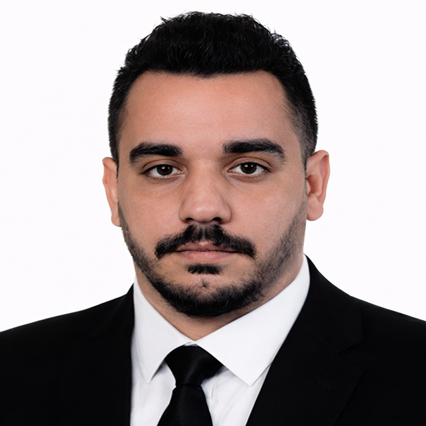 Professional headshot of a man in a black suit and tie against a white background.
