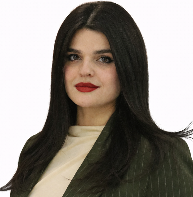 Portrait of a woman with long dark hair, red lipstick, wearing a green pinstripe blazer and beige top.