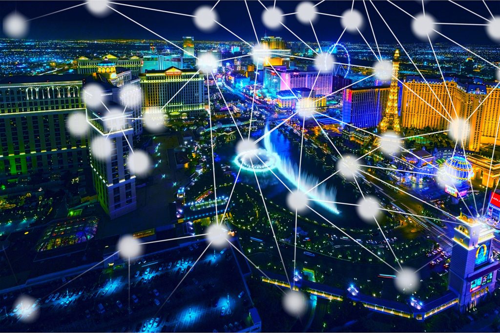 Night cityscape at night with a glowing network of interconnected nodes and lines across the skyline, representing connectivity or a smart city.