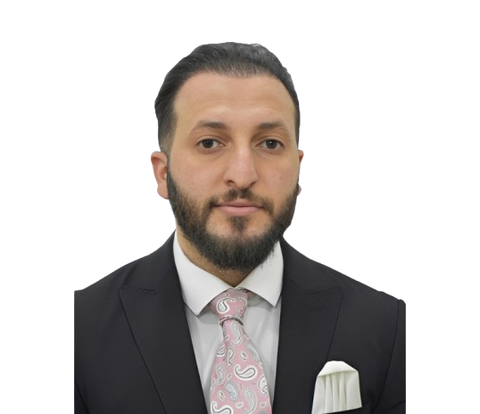 Portrait of a man with dark hair and beard wearing a black suit, white shirt, pink paisley tie, and a white pocket square, facing the camera.