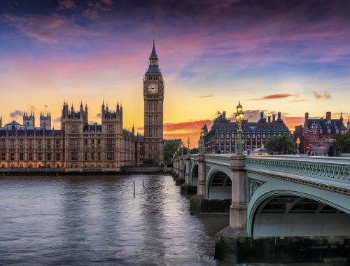 Westminster at sunset with the Houses of Parliament and Big Ben along the River Thames, and Westminster Bridge in the foreground.